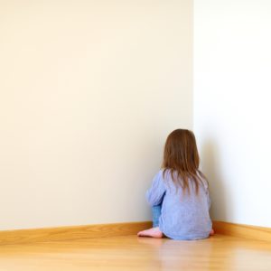 Sad little girl sitting in a corner